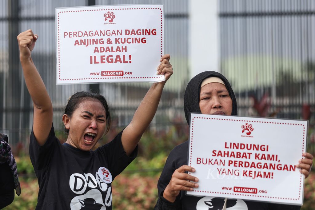 Dua peserta aksi membawa poster berisi tuntutan mereka di depan Kompleks Parlemen, Jakarta, Kamis (1/2/2024).