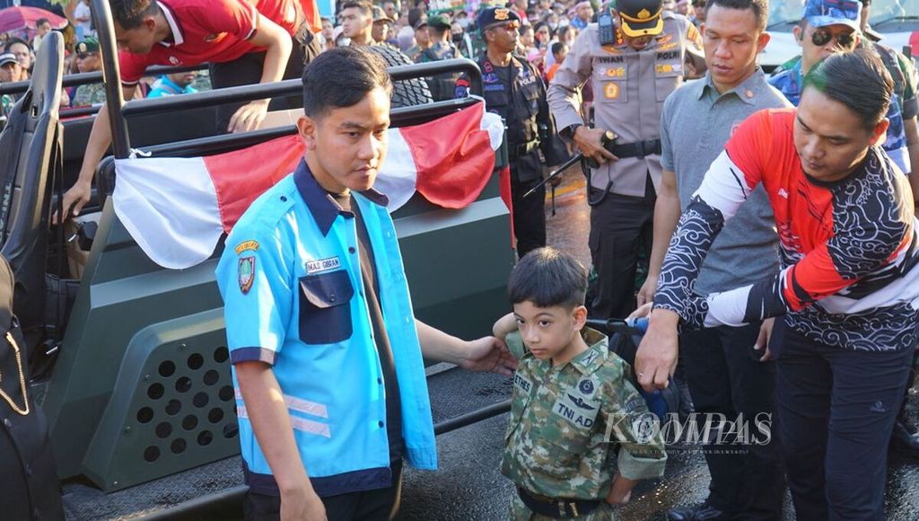 Wali Kota Surakarta Gibran Rakabuming Raka (kiri) mendatangi pawai pembangunan bersama putra sulungnya, Jan Ethes Srinarendra, di Kota Surakarta, Jawa Tengah, Jumat (18/8/2023). 