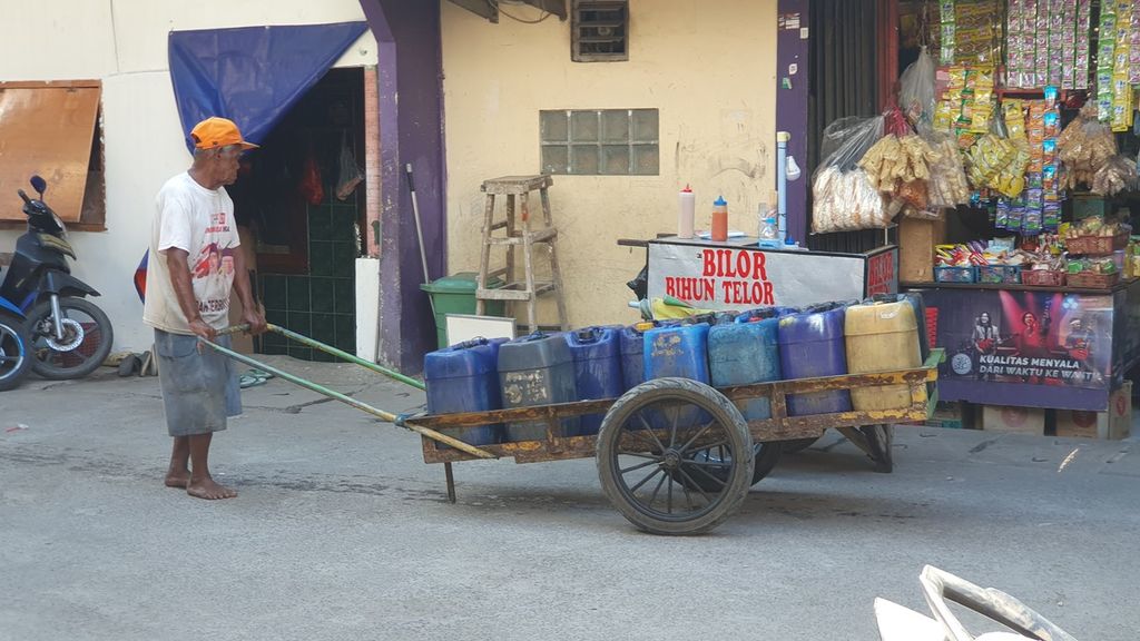 Penjual air keliling mendorong gerobaknya dan menjajakan jeriken berisi air bersih untuk warga Kampung Gedung Pompa, RT 020 RW 017, Kelurahan Penjaringan, Kecamatan Penjaringan, Jakarta Utara.