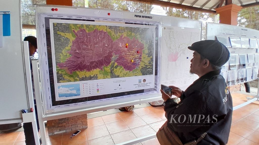 Seorang jurnalis tengah mengamati peta kebakaran lahan di Gunung Arjuno yang ada di Posko Kaliandra, Prigen, Pasuruan, Jawa Timur, Jumat (8/9/2023).