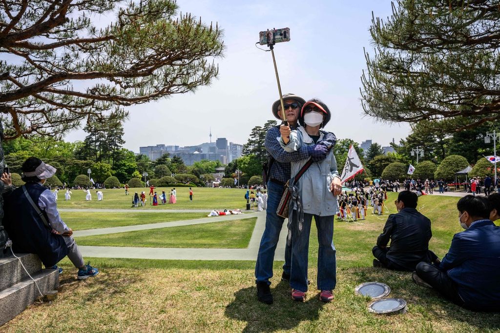 Pengunjung berswafoto di kompleks Gedung Biru, Istana Kepresidenan Korea Selatan di Seoul, 11 Mei 2022. Sesuai janji Presiden Yoon Suk Yeol, Istana Kepresidenan lama itu dibuka untuk umum. (Photo by ANTHONY WALLACE / AFP)