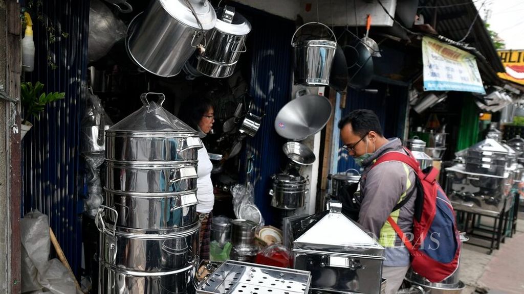 Pengunjung memilih sejumlah perabotan dapur berbahan aluminium di salah satu kios di Jalan Dewi Sartika, Jakarta Timur, Senin (20/9/2021). Meski pandemi berdampak pada terpuruknya perekonomian, para perajin tetap bertahan untuk melayani pelanggan.  