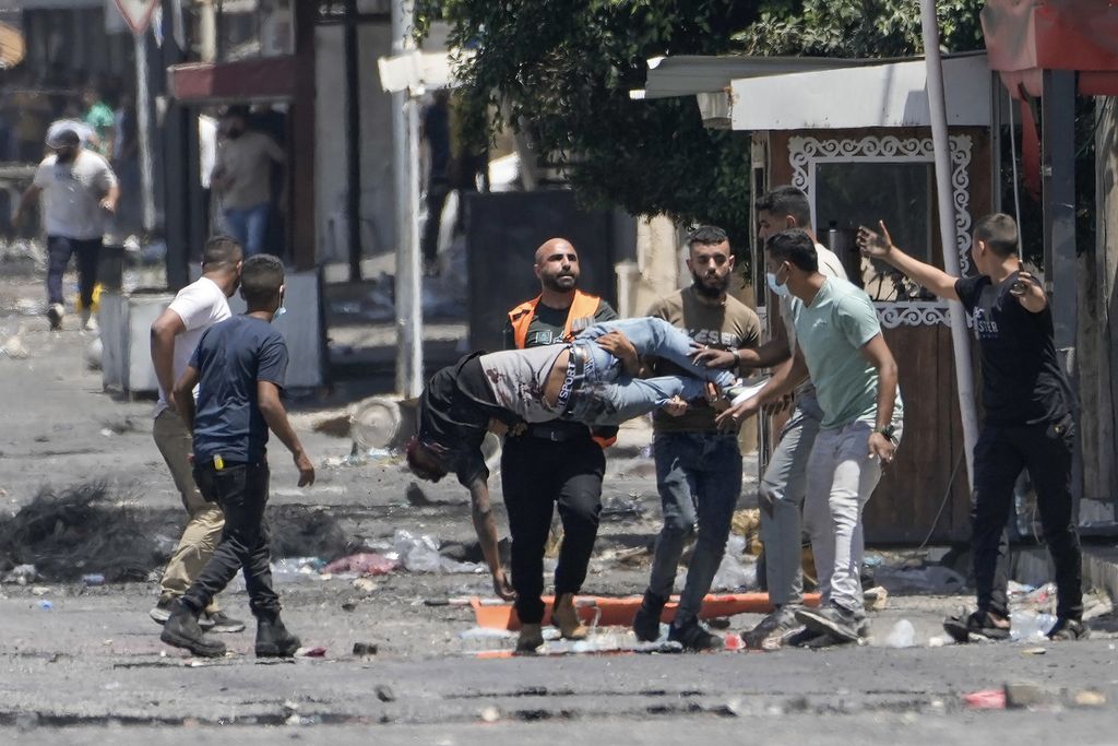 Beberapa warga Palestina membawa tubuh seorang pria yang terluka akibat tembakan militer Israel selama operasi militer di kota Jenin, Tepi Barat, Palestina, Selasa (4/7/2023). 