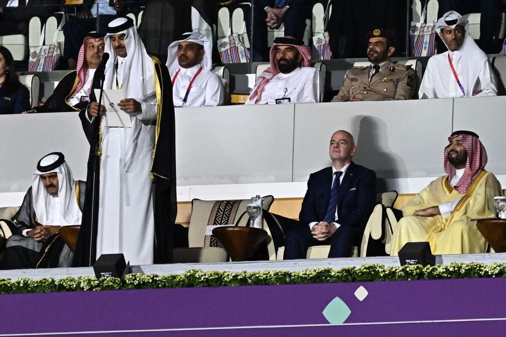 Emir Qatar Sheikh Tamim bin Hamad al-Thani (berdiri) menyampaikan pidato, sementara Presiden FIFA Gianni Infantino (kedua dari kanan) dan Putra Mahkota Arab Saudi Pangeran Mohammed bin Salman al-Saud (kanan) duduk di sebelahnya, pada upacara pembukaan Piala Dunia 2022 di Stadion Al-Bayt, Al Khor, utara Doha, Qatar, Minggu (20/11/2022). 