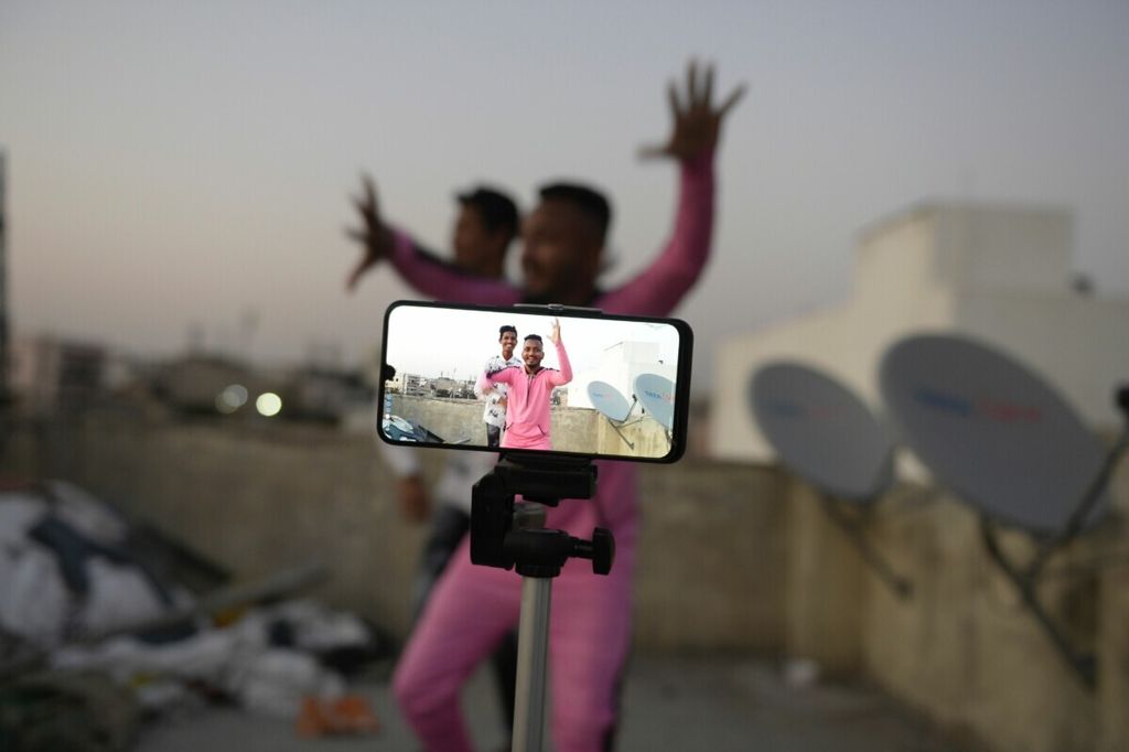 Dua anak muda beraksi di depan kamera telepon seluler saat membuat video Tiktok di teras rumah mereka di Hyderabad, India, 14 Februari 2020. 