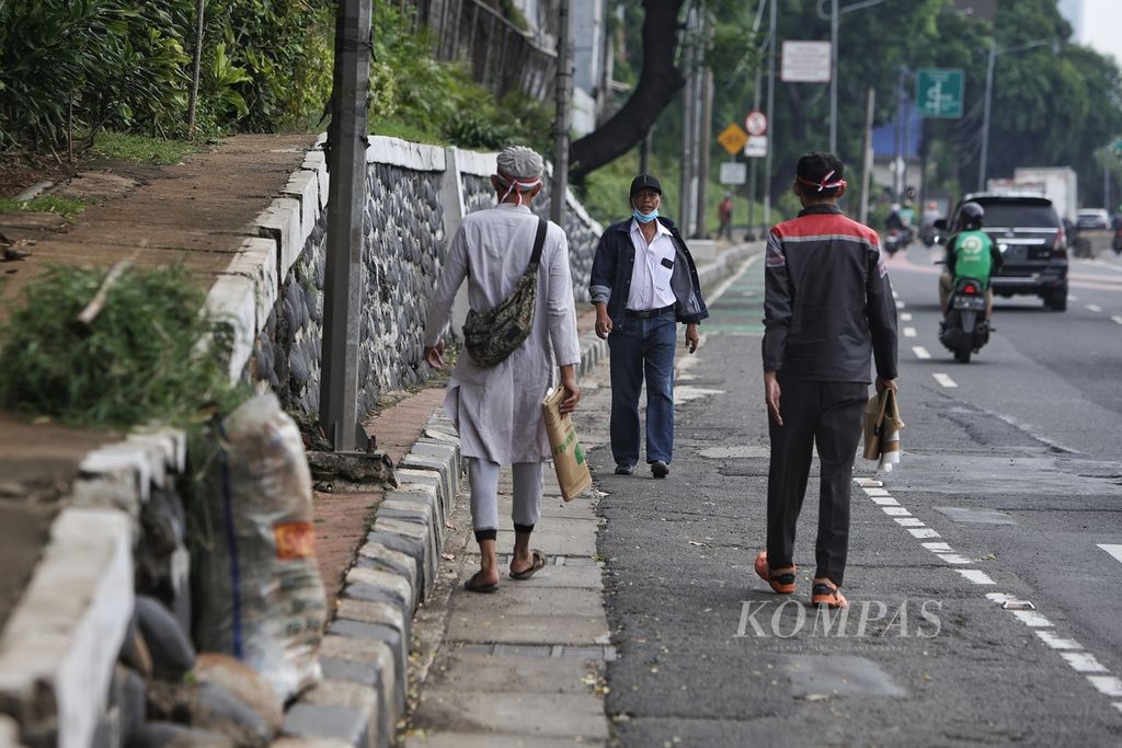 Warga berjalan di aspal karena kondisi trotoar yang tidak ideal di Jalan Gatot Subroto, Jakarta, Jumat (1/3/2024). Meski proyek revitalisasi trotoar terus digiatkan, kondisi trotoar di sejumlah wilayah di Jakarta masih menyulitkan pejalan kaki untuk melintas. 