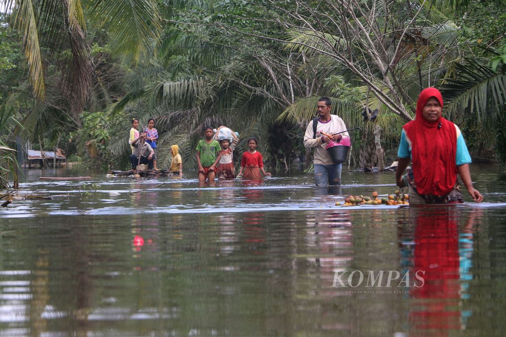 Warga Desa Cot U Sibak, Kecamatan Lhoksukon, Kabupaten Aceh Utara, Aceh, mengarungi banjir yang melanda desa mereka. Aceh Utara kian sering dilanda banjir saat musim hujan.