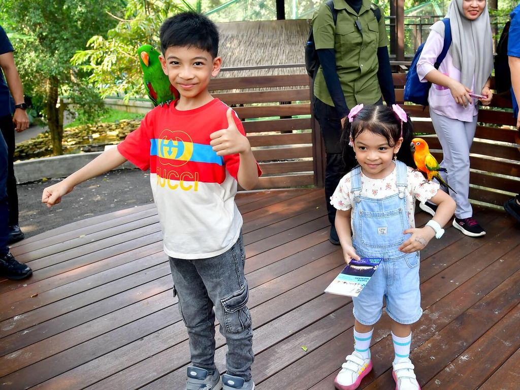 Dua cucu Presiden Joko Widodo, Jan Ethes Srinarendra dan La Lembah Manah, berpose dengan burung bertengger di pundak masing-masing di Taman Mini Indonesia Indah, Jakarta, Sabtu (8/6/2024).