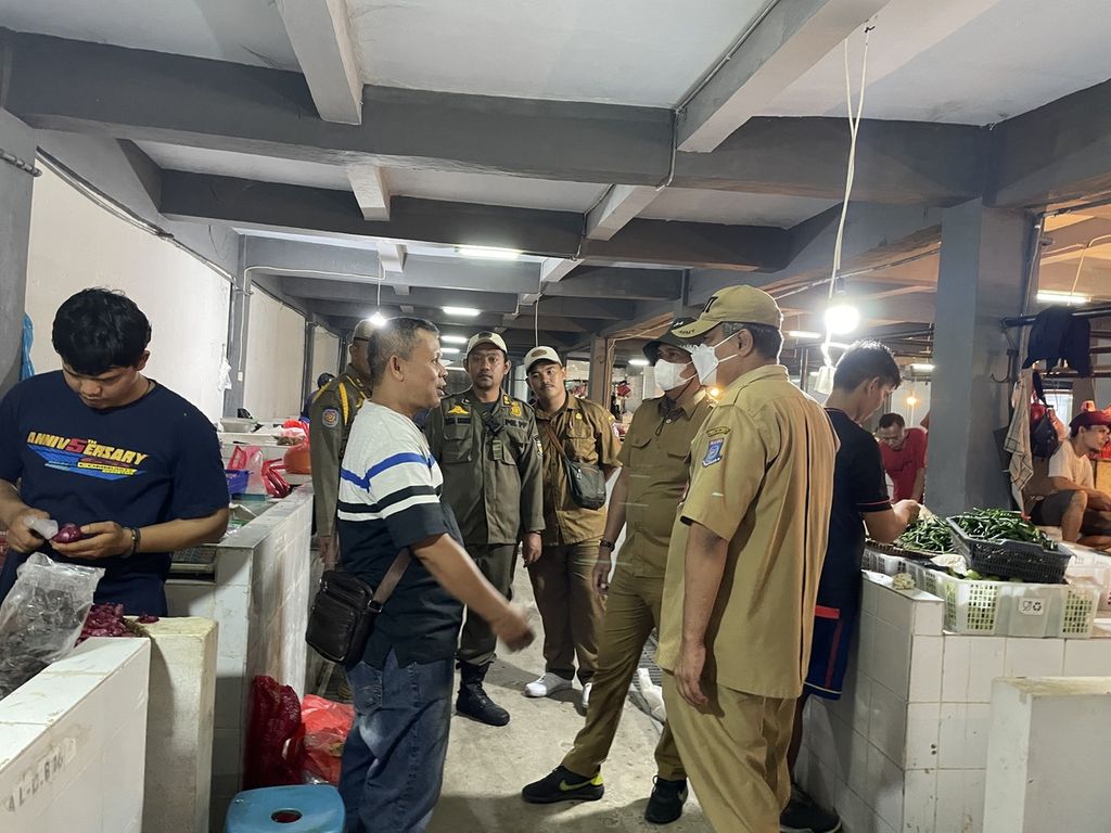 Kepala Dinas Perindustrian dan Perdagangan Kota Tangsel Heru Agus Santoso (kanan) berbincang dengan salah satu pedagang di lantai dasar gedung 1 Pasar Ciputat, Tangerang Selatan, Senin (27/2/2023).