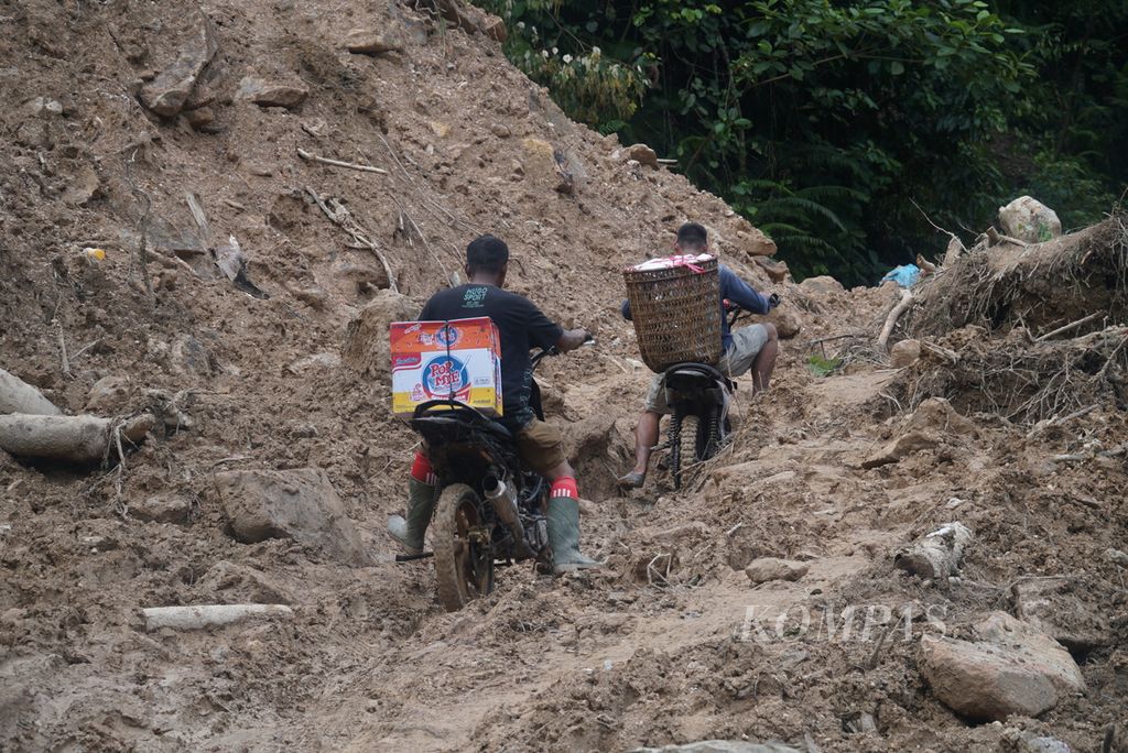 Pengendara sepeda motor <i>trail</i> melewati salah satu jalan yang terputus akibat longsor untuk mengantarkan bantuan logistik kepada korban banjir bandang di Kampung Langgai, Nagari Ganting Mudik Utara Surantih, Kecamatan Sutera, Kabupaten Pesisir Selatan, Sumatera Barat, Rabu (13/3/2024). 