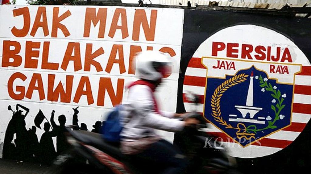 Warga melintas di mural Persija Jakarta di kawasan Pesanggrahan, Jakarta Selatan, Selasa (28/11). Tanggal 28 November merupakan ulang tahun klub sepak bola berjuluk ”Macan Kemayoran” yang telah berusia 89 tahun itu.