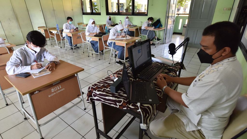 Guru sejarah Alloysius Bram membimbing muridnya secara tatap muka dan juga daring di SMA Negeri 86 Jakarta, Jumat (29/10/2021). Dalam sepekan, para siswa di sekolah tersebut menghadiri satu kali pembelajaran tatap muka atau PTM.