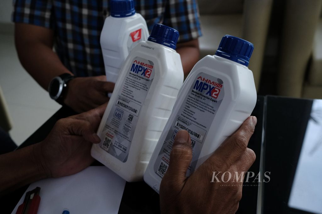 Seorang petugas menyandingkan dua kemasan botol oli asli dan palsu (kiri ke kanan) merek AHM MPX2 di Bogor, Jawa Barat, Rabu (9/11/2022). Kemasan oli palsu tampak menyaru sehingga sulit dibedakan dengan merek asli.