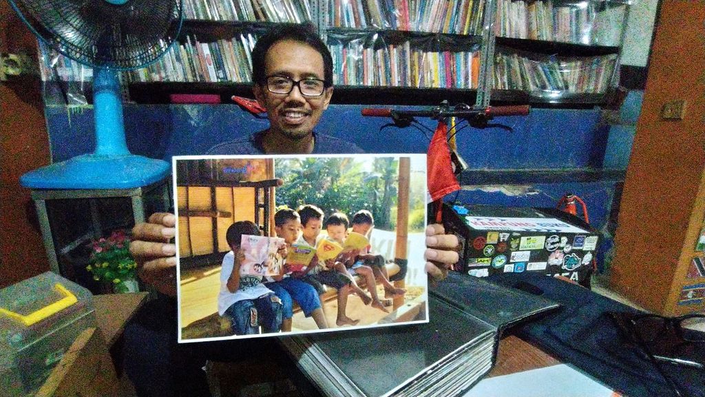 Edi Dimyati (44), pendiri Taman Baca Masyarakat Kampung Buku, tengah menunjukkan arsip fotonya, Kelurahan Cibubur, Kecamatan Ciracas, Jakarta Timur, Rabu (21/12/2022).