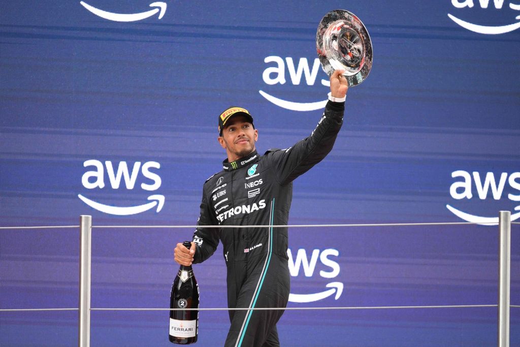 Pebalap Mercedes, Lewis Hamilton, melakukan selebrasi di podium sebagai pemenang kedua pada balapan Formula 1 seri Spanyol di Sirkuit Catalunya, Minggu (4/6/2023) malam.  Hamilton akan terus berada di belakang kemudi Mercedes sampai musim 2025.