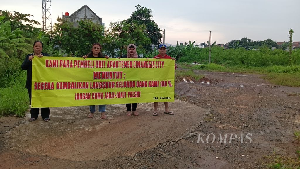 Para korban berdiri di tanah kosong yang rencananya akan berdiri apartemen Cimanggis City, Kota Depok, Jawa Barat, (16/12/2022). Mereka membentangkan spanduk protes dan tuntutan kepada pihak pengembang agar mengembalikan uang yang sudah mereka bayarkan.