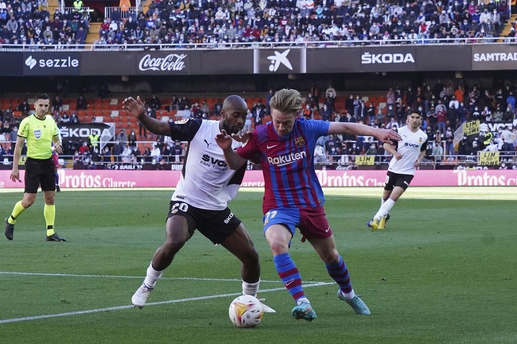 Pemain Barcelona, Frenkie de Jong (kanan), berebut bola dengan pemain Valencia, Dimitri Foulquier, pada laga Liga Spanyol, Senin (21/2/2022) dini hari WIB, di Stadion Mestalla, Valencia. De Jong mencetak satu gol dan membawa Barcelona menang 4-1.