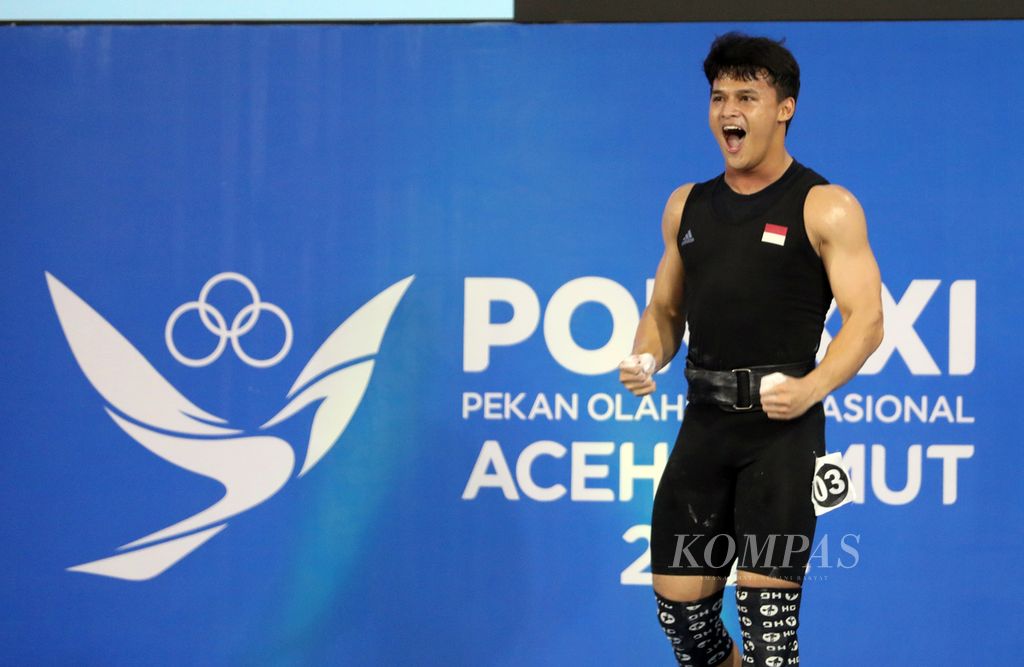 Lifter Banten, Rizki Juniansyah, melakukan selebrasi seusai menuntaskan angkatan <i>clean and jerk</i> berbobot 200 kg sekaligus mempertajam rekor nasional atas namanya sendiri dalam kesempatan ketiga pada cabang angkat besi kelas 89 kg PON Aceh-Sumut 2024 di Banda Aceh, Sabtu (7/9/2024).