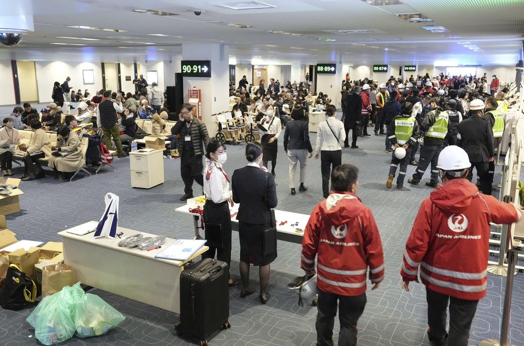 Pegawai maskapai Japan Airlines berdiri di Bandara Haneda di Tokyo, Jepang, Selasa (2/1/2024). Pesawat penumpang bertabrakan dengan pesawat Penjaga Pantai Jepang dan terbakar di landasan Bandara Haneda pada Selasa.