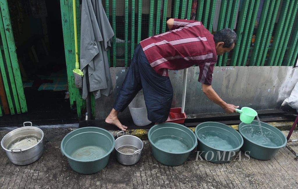 Masdeni transfers rainwater from a bucket to a smaller container in front of a resident's house in Kampung Baru Tengah, Balikpapan Barat District, Balikpapan City on November 4th, 2023. Amidst a limited water supply, residents collect rainwater to fulfill their daily water needs.