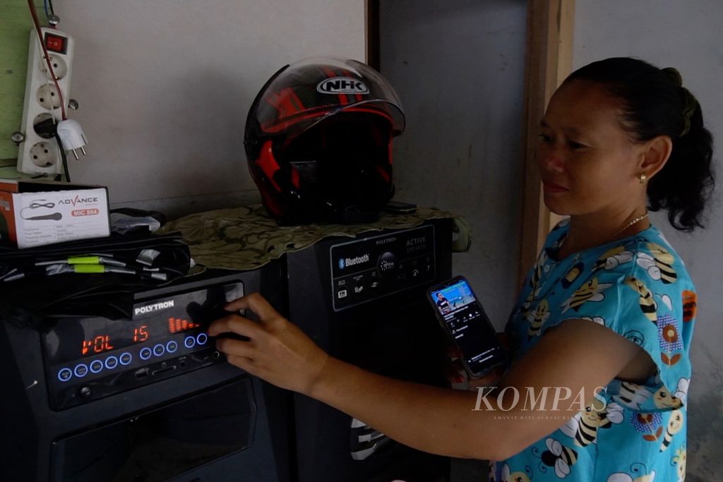Jelita Makalalag menaikkan volume suara pelantang untuk mendengarkan lagu, Jumat (15/7/2022), di Desa Mengkang, Bolaang Mongondow, Sulut.