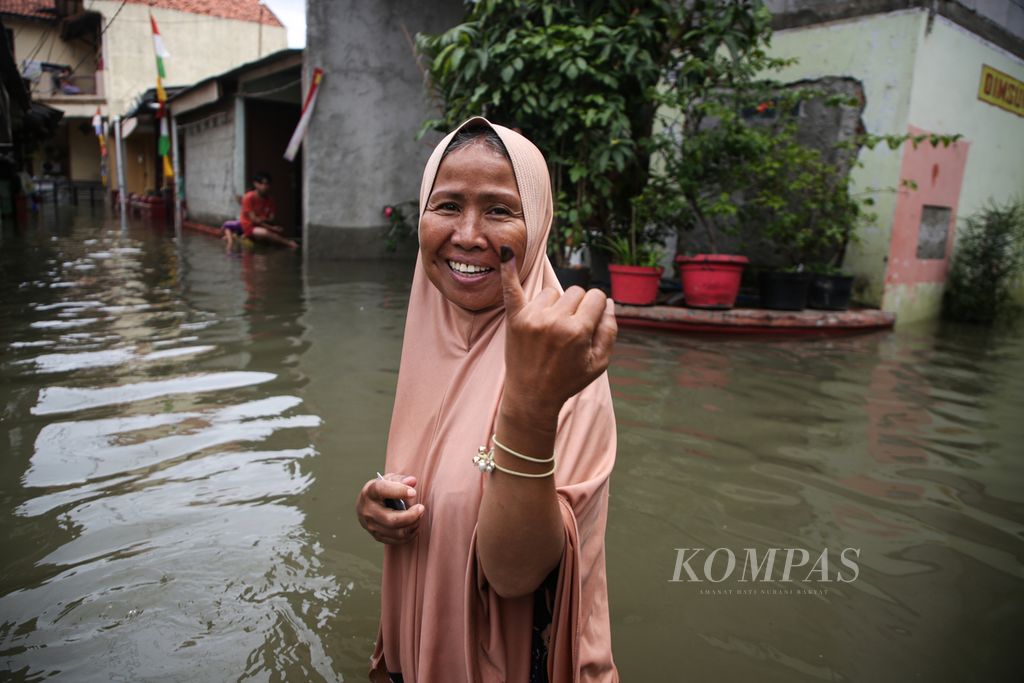 Warga tersenyum saat memperlihatkan jari yang bertinta setelah menyalurkan suara pada Pemilu 2024 di TPS 20 di Kelurahan Larangan Utara, Larangan, Kota Tangerang, Banten, Rabu (14/2/2024). Meskipun kediamannya terendam banjir, warga tersebut tetap antusias menuju TPS untuk menyalurkan suara. 