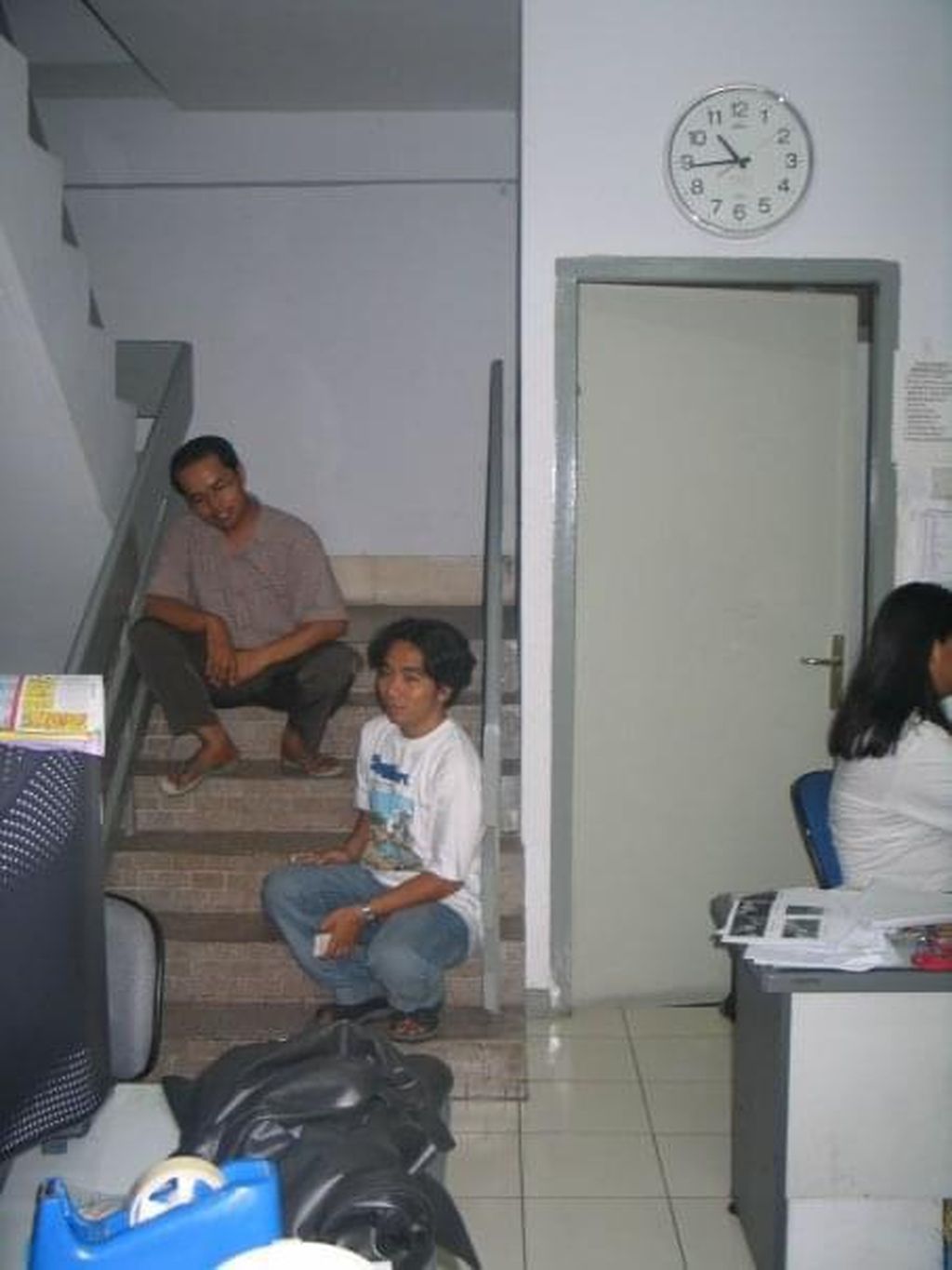 Karyawan bagian tata letak koran, Gandi (kiri), bersama wartawan Kompas, Khaerudin, duduk di tangga Kantor <i>Kompas</i> Biro Jawa Timur di Jalan Kombes Pol M Duryat, Surabaya, sekitar 2004-2005. 