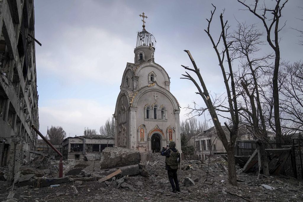 Seorang anggota militer Ukraina berdiri di depan sisa bangunan gereja yang masih berdiri setelah lingkungan di sekitarnya rata dengan tanah karena serangan artileri berat di kota Mariupol, Ukraina, Kamis (10/3/2022).