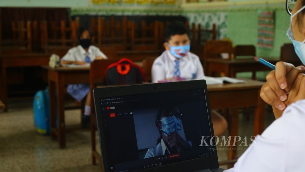 Seorang guru melakukan <i>blended learning</i> yang menggabungkan pembelajaran tatap muka dan pembelajaran jarak jauh dalam waktu bersamaan di SD Katolik St Maria Banyuwangi, Jawa Timur, Rabu (24/2/2021). 