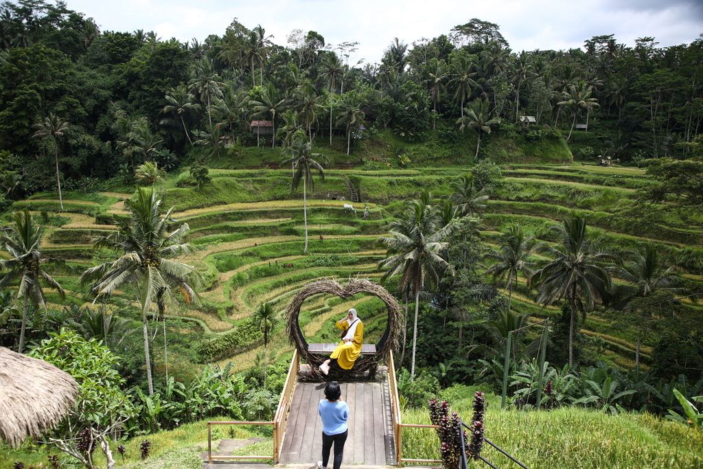 Wisatawan domestik berfoto dengan latar belakang area persawahan di Tegalalang, Kabupaten Gianyar, Bali, Minggu (21/11/2021).  