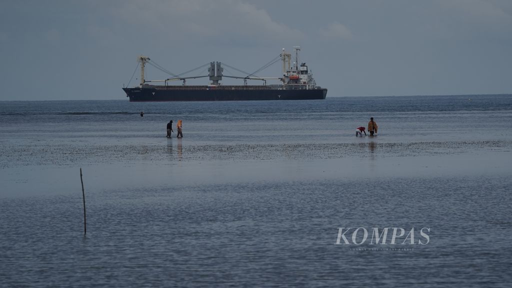 Nelayan mencari ikan di pantai dengan latar belakang kapal di Desa Lililef, di Kecamatan Weda Tengah, Kabupaten Halmahera Tengah, Provinsi Maluku Utara.