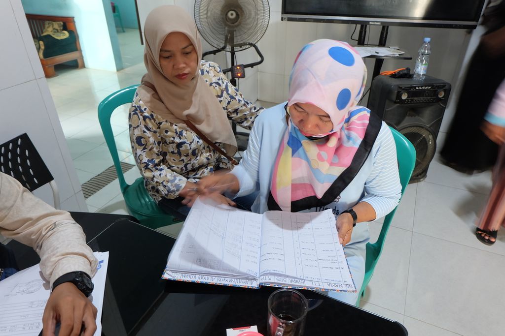 Inge Martini, Ketua Satuan Tugas Pelindungan Pekerja Migran Indonesia (PMI) Desa Babakangebang di Kecamatan Babakan, Kabupaten Cirebon, Jawa Barat, pada Jumat (21/7/2023) memeriksa data PMI asal desa tersebut. 
