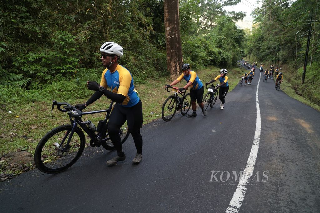 Para pabalap menuntun sepedanya saat melintasi tanjakan di Tamanjaya, Ciemas, Sukabumi, Jawa Barat, pada etape ke-1 Cycling de Jabar 2023, Sabtu (8/7/2023). 