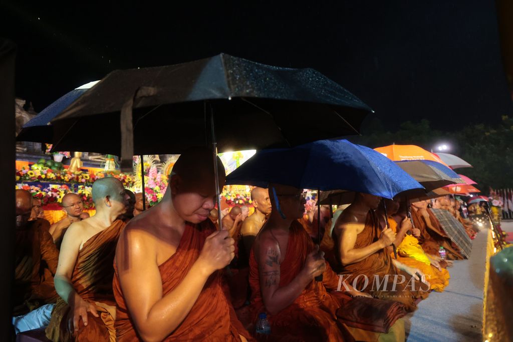Sejumlah biksu berdoa sambil menggunakan payung saat hujan turun ketika umat Buddha bersiap menyambut detik-detik Waisak dalam peringatan Tri Suci Waisak 2568 BE/2024 di kompleks Candi Borobudur, Magelang, Jawa Tengah, Kamis (23/5/2024). 
