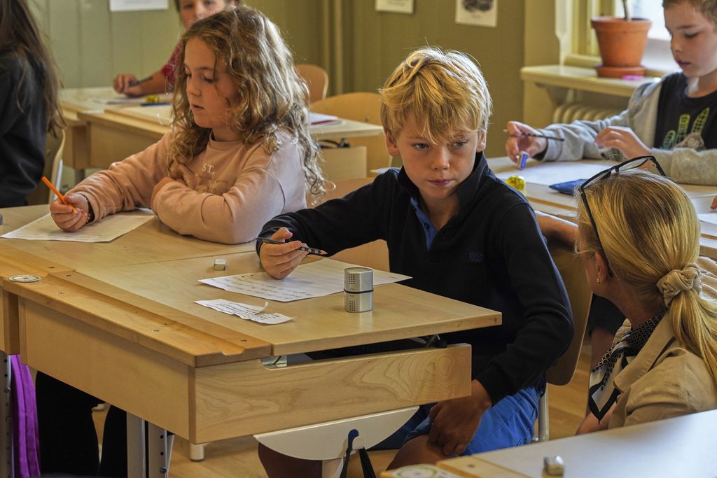Seorang guru (kanan) membantu siswa-siswanya menulis dengan tangan di Sekolah Dasar Djurgardsskolan, di Stockholm, Swedia, Kamis (31/8/2023). 