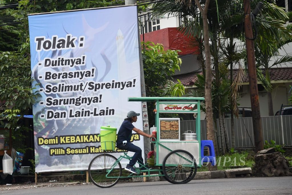 Warga melintas di dekat spanduk anjuran untuk menolak pemberian dalam Pilkada Kota Surabaya di Jalan Kombes Pol M Duriyat, Surabaya, Jawa Timur, Senin (7/12/2020). Hal tersebut dilakukan untuk menciptakan pilkada yang bermartabat.