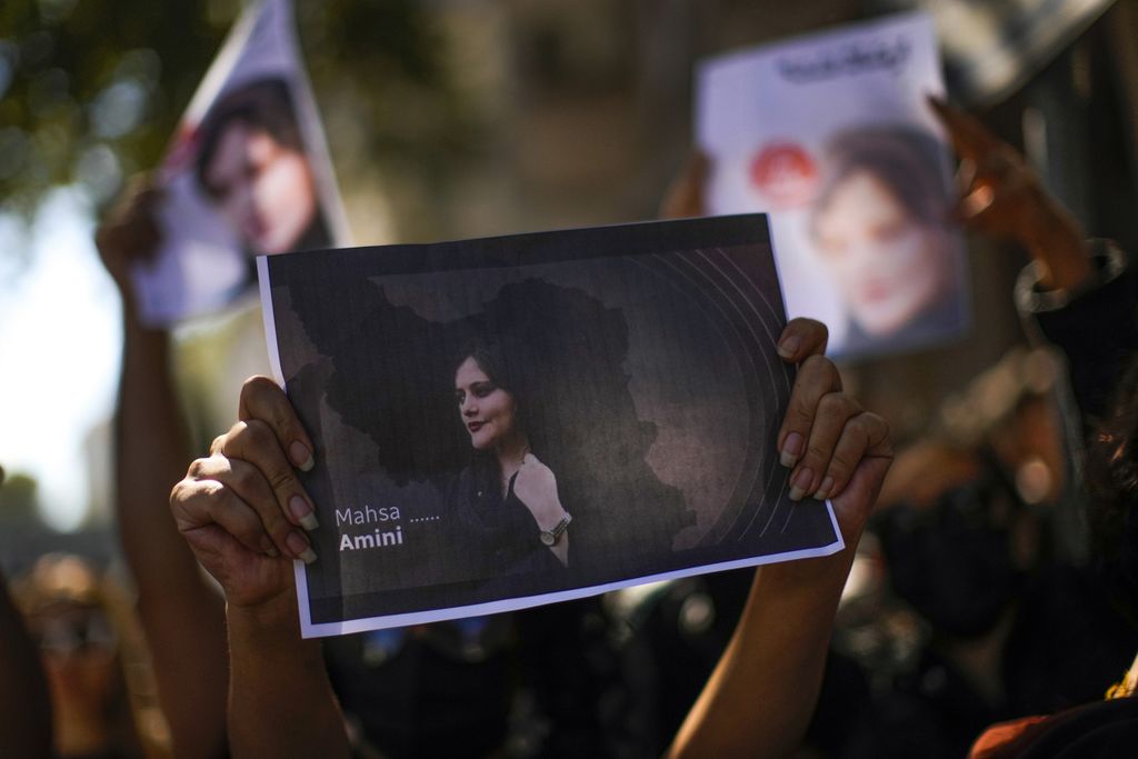 Seorang perempuan pengunjuk rasa mengangkat foto Mahsa Amini (22), saat berdemonstrasi di Konsulat Jendera Iran di Istanbul, Turki, Rabu (21/9/2022). Amini tewas setelah diduga mengalami kekerasan oleh polisi selama menjalani tahanan. 