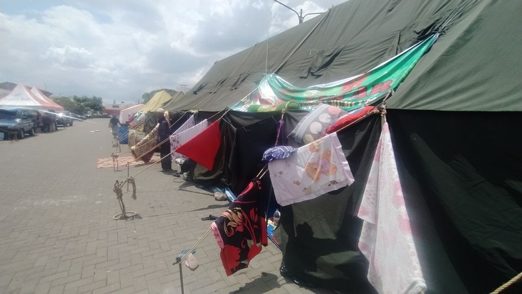 Warga yang mengungsi memanfaatkan tali-tali tenda untuk menjemur handuk, di Pos Pengungsian Alun-alun Cianjur, Jawa Barat, Senin (28/11/2022).