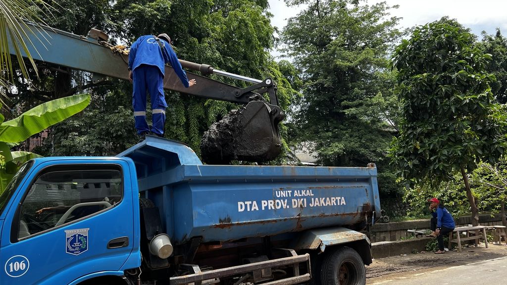 Petugas memberi aba-aba kepada operator alat berat saat menuang lumpur ke dalam <i>dump truck</i> di Jalan Matraman Dalam, Jakarta Pusat, Jumat (11/11/2022).