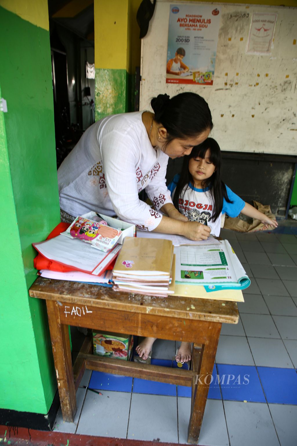 Ibu Rika mendampingi putrinya Ninda, siswa kelas II SD menyelesaikan tugas pendidikan agama Islam dalam pembelajaran jarak jauh dari rumahnya yang berada di lingkungan SD Negeri Cipulir 05, Jakarta Selatan, 