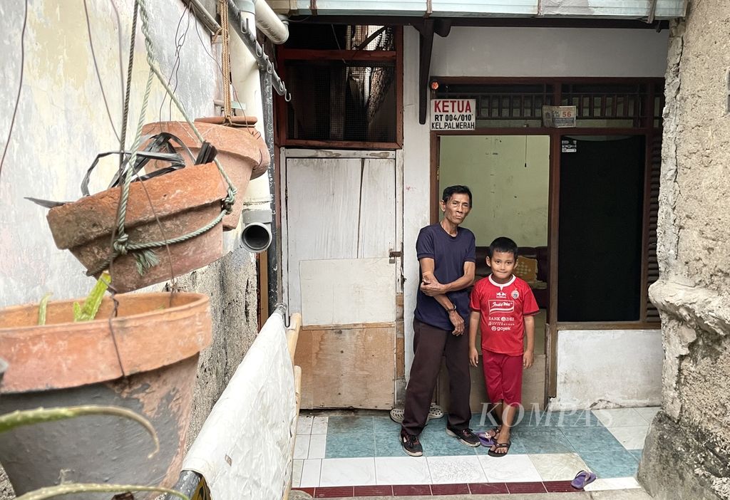 Marmo (70) bersama cucunya berpose di rumahnya di Kelurahan Palmerah, Jakarta Barat, Jumat (2/9/2022). Dia telah 14 tahun menjabat sebagai Ketua RT 004/RW 10 dengan warga lebih dari 100 keluarga. Marmo adalah pensiunan petugas pemadam kebakaran Provinsi DKI.