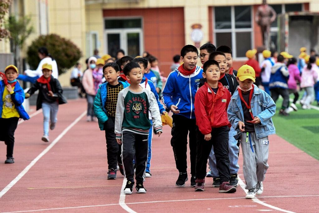 Para siswa berjalan di arena bermain di sebuah sekolah dasar di Qingdao, Provinsi Shandong, China timur, 11 Mei 2021. Biro Pusat Statistik Nasional China, Selasa (17/1/2023), mengumumkan angka pertumbuhan penduduk negaranya berada pada titik terendah sejak 1961. 