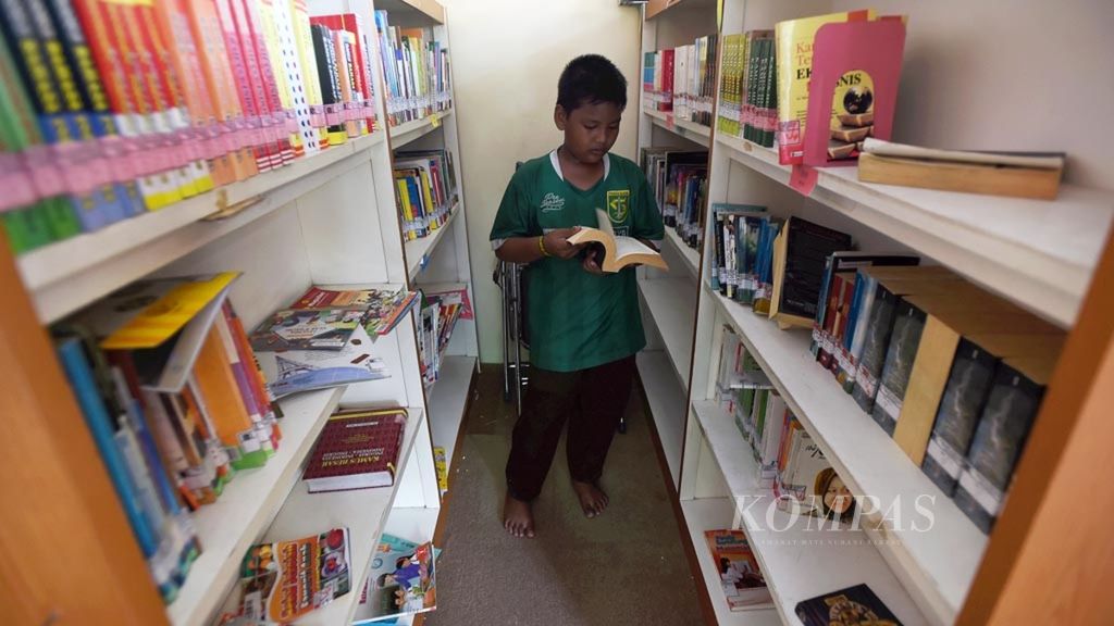 Warga membaca buku di Taman Bacaan Masyarakat RW VI Keluarahan Dukuh Menanggal, Kecamatan Gayungan, Surabaya, Kamis (10/1/2019).