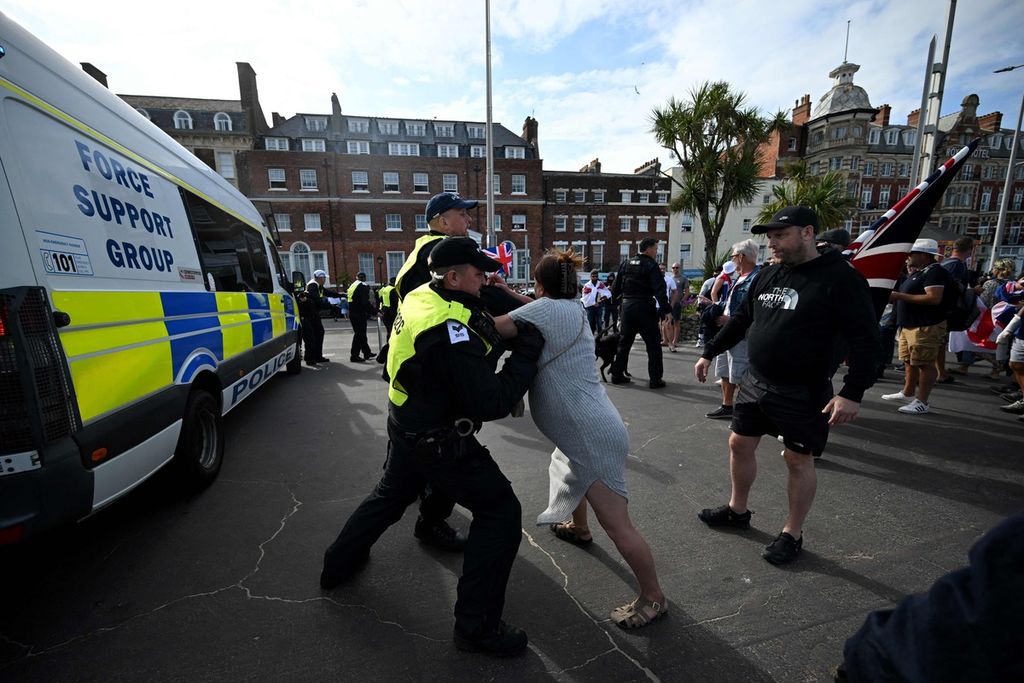 Aparat kepolisian menahan seorang pengunjuk rasa dalam demonstrasi Enough is Enough yang digelar aktivis sayap kanan di Weymouth di kawasan pantai Inggris barat laut, Minggu (4/8/2024). 