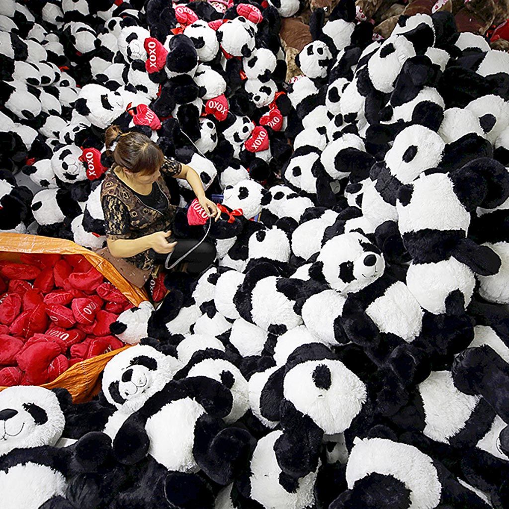 Seorang pekerja memasang hiasan pada boneka panda yang disiapkan menyambut musim liburan Natal dan Tahun Baru   di sebuah pabrik mainan anak-anak di Lianyungang, Provinsi Jiangsu, China. Otoritas China optimistis target pertumbuhan ekonomi 6,5 persen tahun ini akan tercapai. 