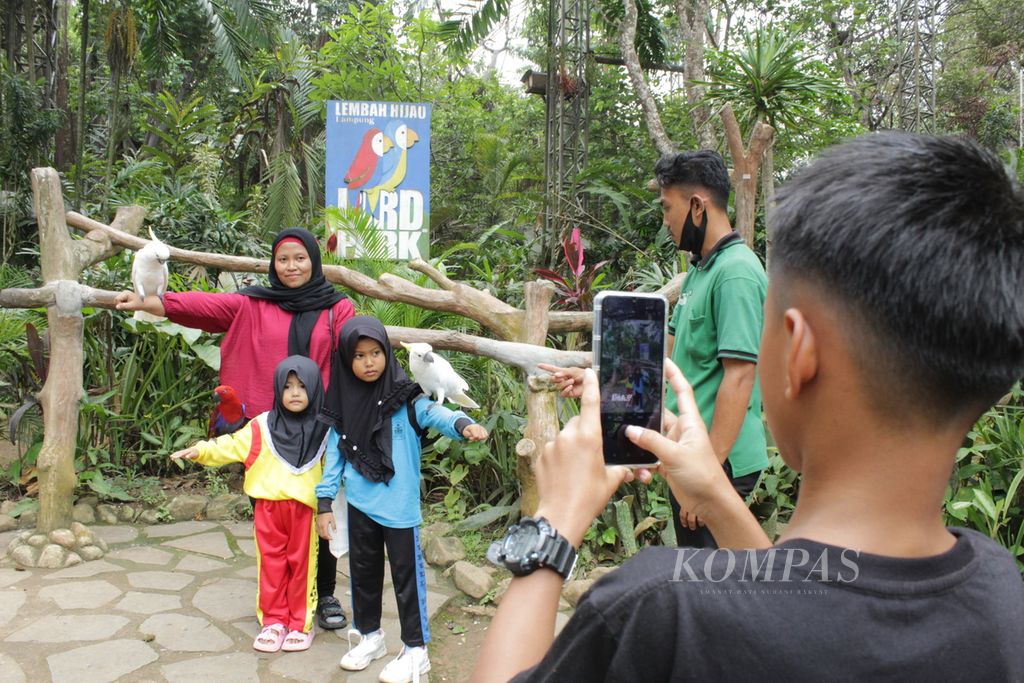 Visitors take pictures with birds at Lembah Hijau Wildlife Park on Monday (29/1/2024).