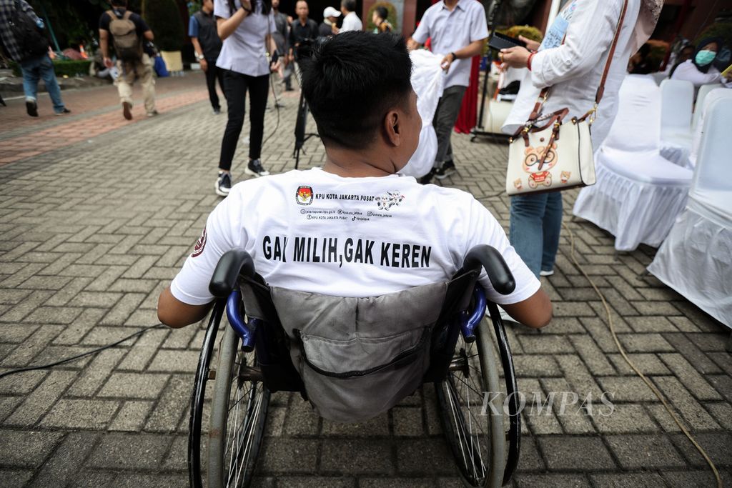 Seorang warga disabilitas mengenakan baju berisi ajakan untuk memilih saat mengikuti simulasi Pemilu 2024 di halaman Kantor Wali Kota Jakarta Pusat, Rabu (17/1/2024). Komisi Pemilihan Umum (KPU) Jakarta Pusat menggelar simulasi pemungutan dan penghitungan suara di tempat pemilihan suara (TPS). 