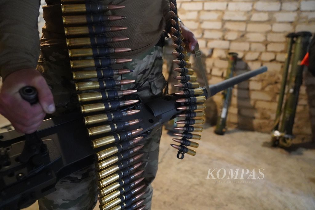 Seorang milisi membawa senapan mesin kaliber .50 Browning di sebuah gudang senjata di bagian selatan Ukraina, Rabu (22/6/2022). Di gudang itu tersimpan pula beberapa ranjau darat buatan sejumlah negara Asia Selatan. 