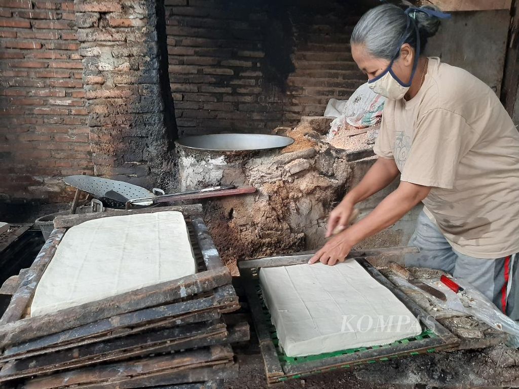 Seorang pelaku usaha menjalankan aktivitas produksi, memotong-motong tahu di rumahnya di Desa Tanjungsari, Kecamatan Borobudur, Kabupaten Magelang, Sabtu (26/3/2022).
