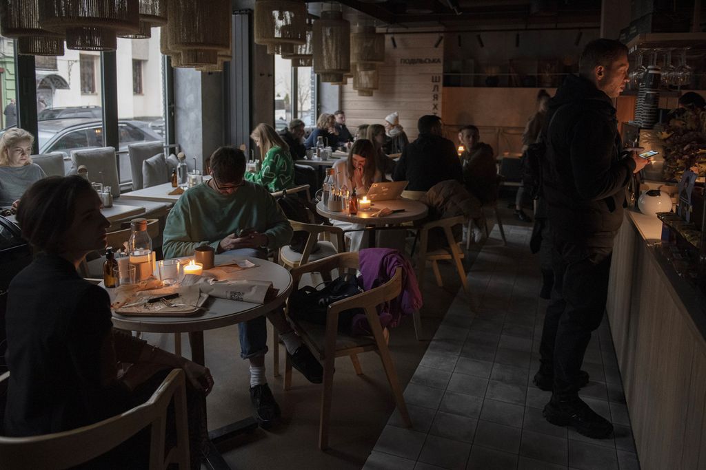 Sejumlah warga duduk di sebuah kafe di kota Kyiv, Ukraina, dalam kondisi gelap, Kamis (3/11/2022). 